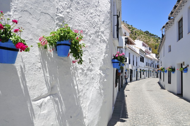 Calle blanca de Mijas pueblo con macetas y sierra al fondo